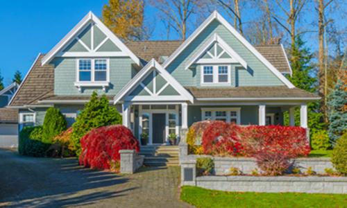 A large house featuring a well-maintained driveway and landscaped garden, showcasing a welcoming exterior